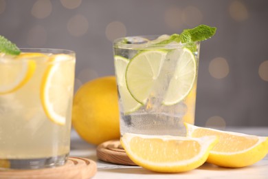 Photo of Tasty citrus cocktails in glasses on white table against blurred lights, closeup