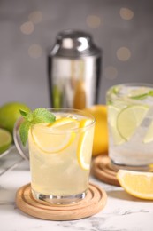 Photo of Tasty citrus cocktails in glasses on white marble table against blurred lights, closeup