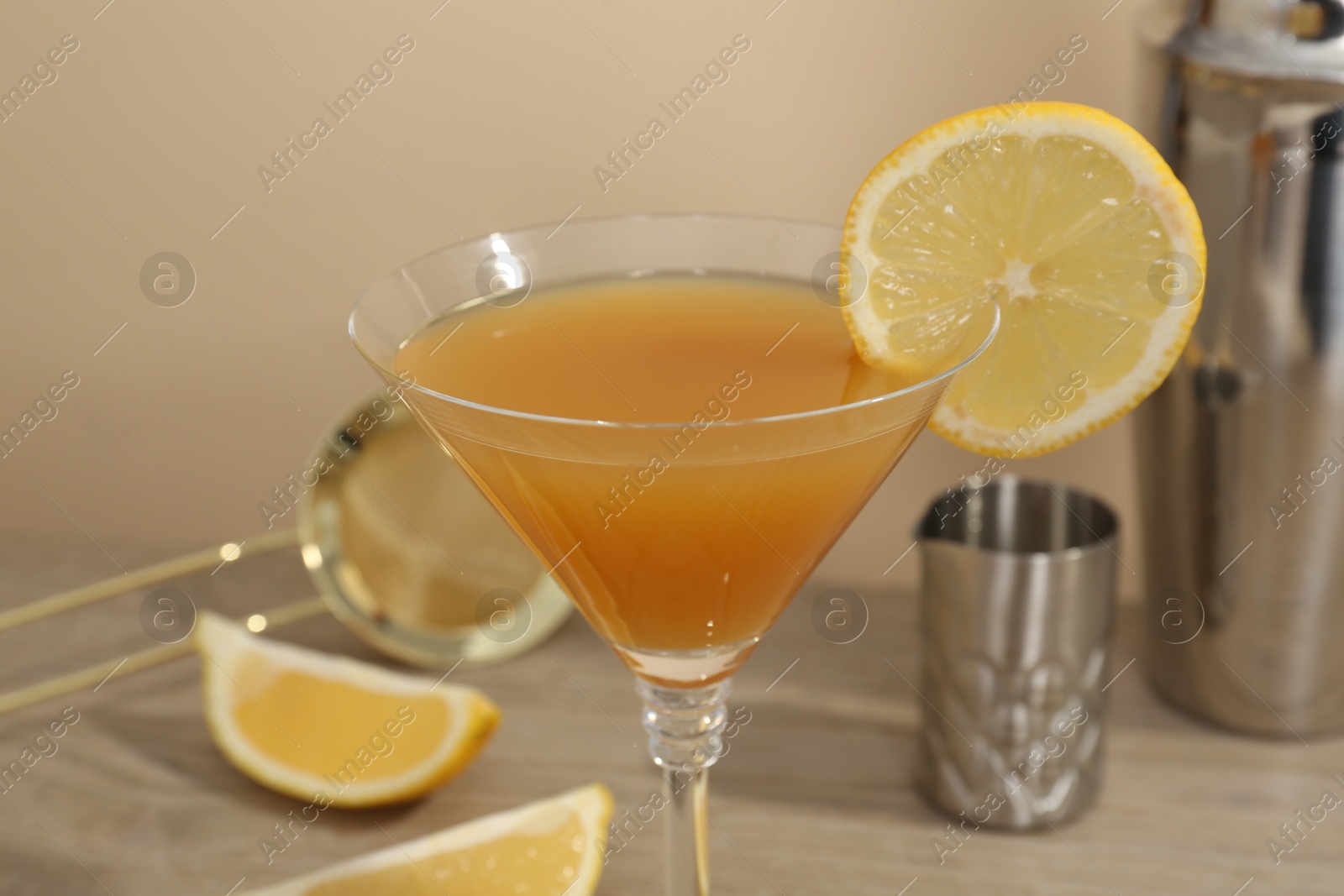 Tasty lemon cocktail in glass and bartender equipment on wooden table, closeup Photo of Tasty lemon cocktail in glass and bartender equipment on wooden table, closeup