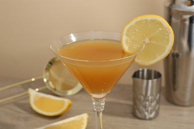 Photo of Tasty lemon cocktail in glass and bartender equipment on wooden table, closeup