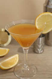 Photo of Tasty lemon cocktail in glass and bartender equipment on wooden table, closeup