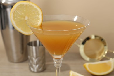 Photo of Tasty lemon cocktail in glass and bartender equipment on table, closeup