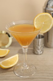 Photo of Tasty lemon cocktail in glass and bartender equipment on wooden table, closeup