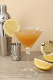 Photo of Tasty lemon cocktail in glass and bartender equipment on wooden table, closeup