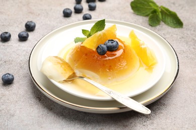 Photo of Tasty panna cotta with orange, blueberries and mint on light grey table, closeup