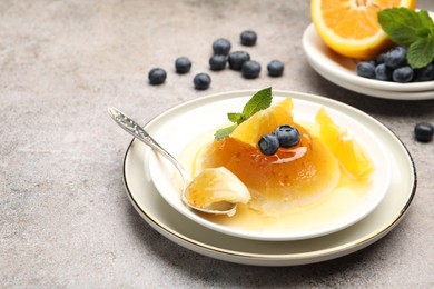 Photo of Tasty panna cotta with orange, blueberries and mint on light grey table, closeup. Space for text