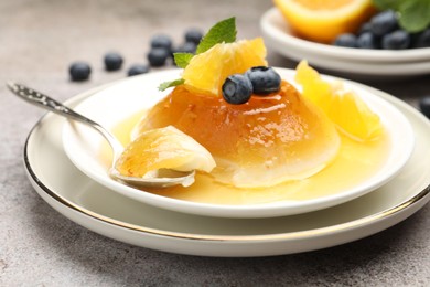 Photo of Tasty panna cotta with orange, blueberries and mint on light grey table, closeup