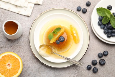Photo of Tasty panna cotta with orange, blueberries and mint on light grey table, flat lay