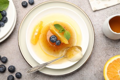 Photo of Tasty panna cotta with orange, blueberries and mint on light grey table, flat lay
