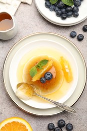 Photo of Tasty panna cotta with orange, blueberries and mint on light grey table, flat lay