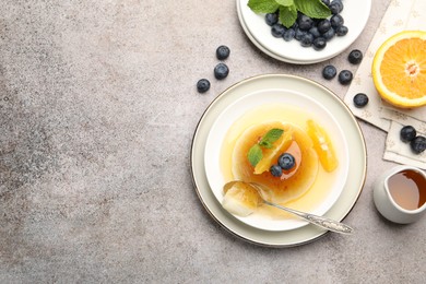 Photo of Tasty panna cotta with orange, blueberries and mint on light grey table, flat lay. Space for text