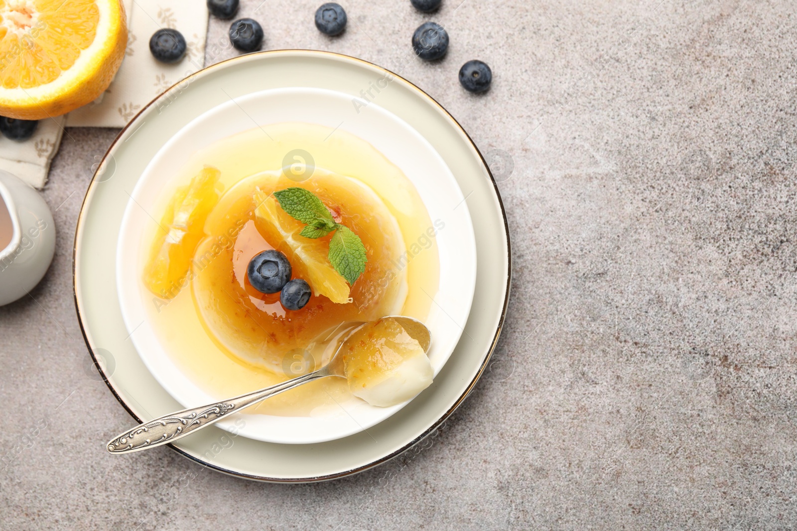 Photo of Tasty panna cotta with orange, blueberries and mint on light grey table, flat lay. Space for text