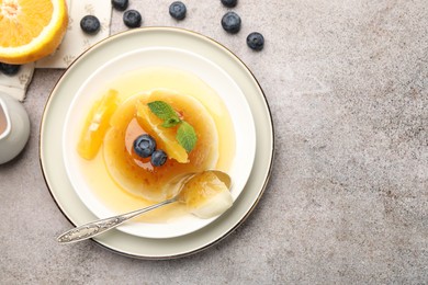 Photo of Tasty panna cotta with orange, blueberries and mint on light grey table, flat lay. Space for text
