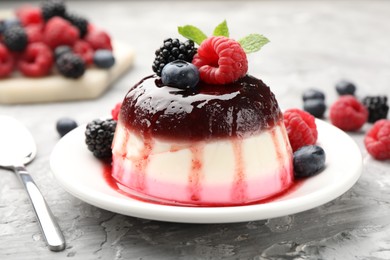 Photo of Tasty panna cotta with berries and jam on light grey table, closeup