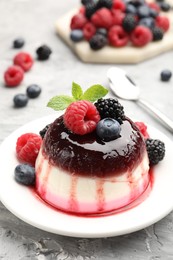 Photo of Tasty panna cotta with berries and jam on light grey table, closeup