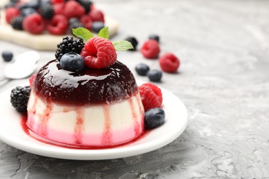 Photo of Tasty panna cotta with berries and jam on light grey table, closeup. Space for text