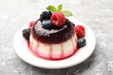 Photo of Tasty panna cotta with berries and jam on light grey table, closeup