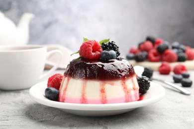 Photo of Tasty panna cotta with berries and jam on light grey table, closeup