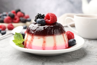 Photo of Tasty panna cotta with berries and jam on light grey table, closeup