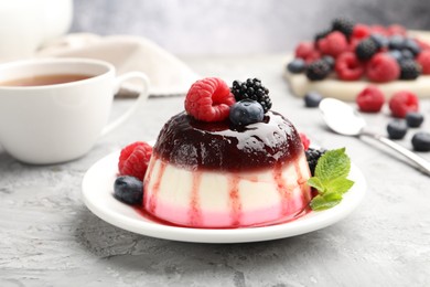 Photo of Tasty panna cotta with berries and jam on light grey table, closeup