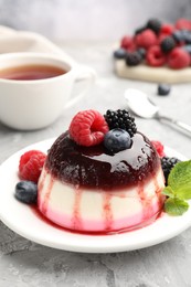 Photo of Tasty panna cotta with berries and jam on light grey table, closeup
