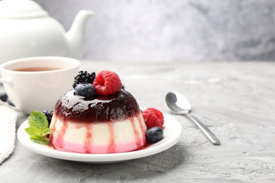 Photo of Tasty panna cotta with berries and jam on light grey table, closeup. Space for text