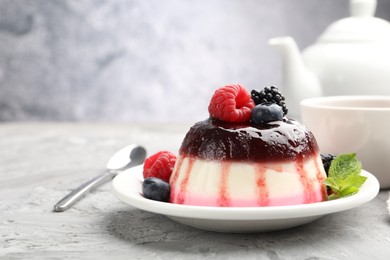 Photo of Tasty panna cotta with berries and jam on light grey table, closeup