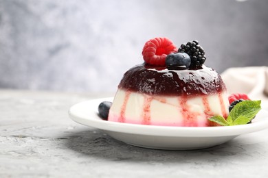 Photo of Tasty panna cotta with berries and jam on light grey table, closeup. Space for text