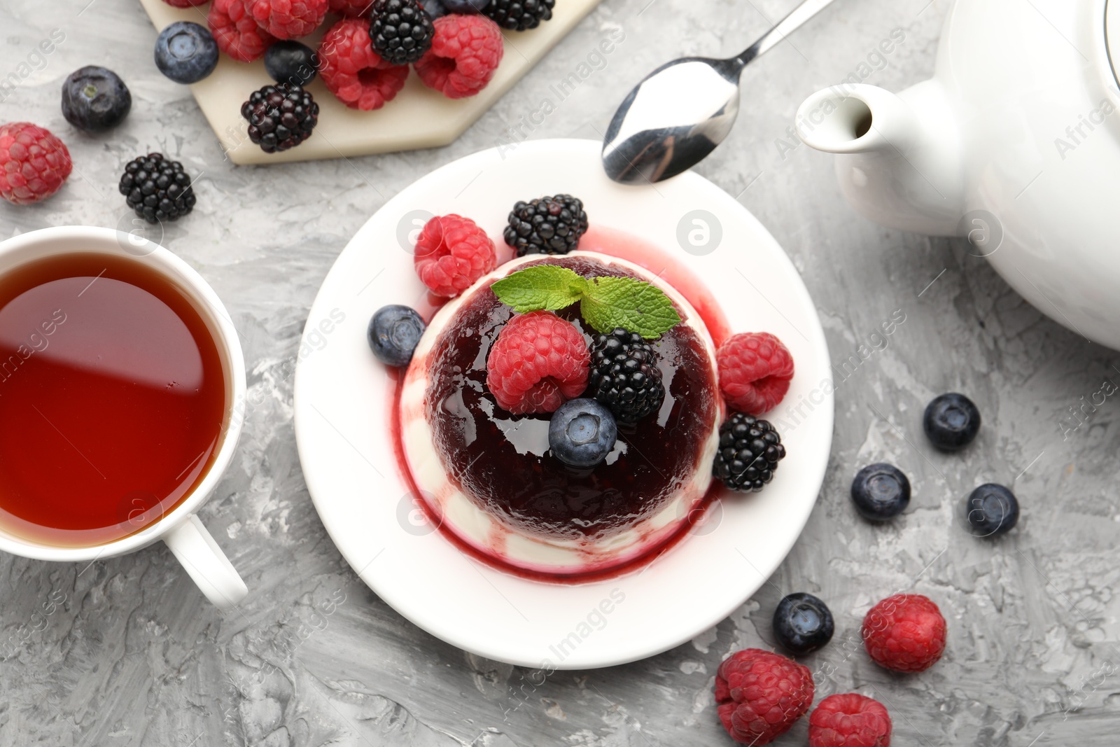 Photo of Tasty panna cotta with berries and jam on light grey table, flat lay