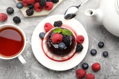 Photo of Tasty panna cotta with berries and jam on light grey table, flat lay