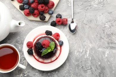 Photo of Tasty panna cotta with berries and jam on light grey table, flat lay. Space for text