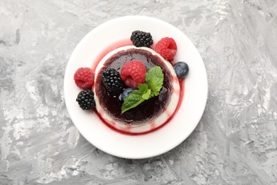 Photo of Tasty panna cotta with berries and jam on light grey table, top view