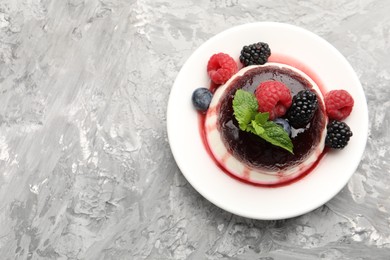 Photo of Tasty panna cotta with berries and jam on light grey table, top view. Space for text