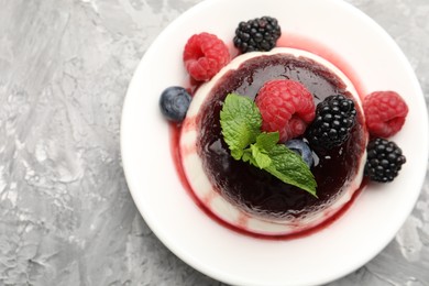Photo of Tasty panna cotta with berries and jam on light grey table, top view
