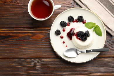 Photo of Tasty panna cotta with blackberries, mint and sauce on wooden table, flat lay. Space for text