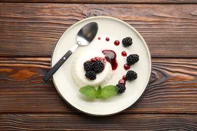 Photo of Tasty panna cotta with blackberries, mint and sauce on wooden table, top view