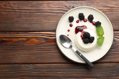 Photo of Tasty panna cotta with blackberries, mint and sauce on wooden table, top view. Space for text
