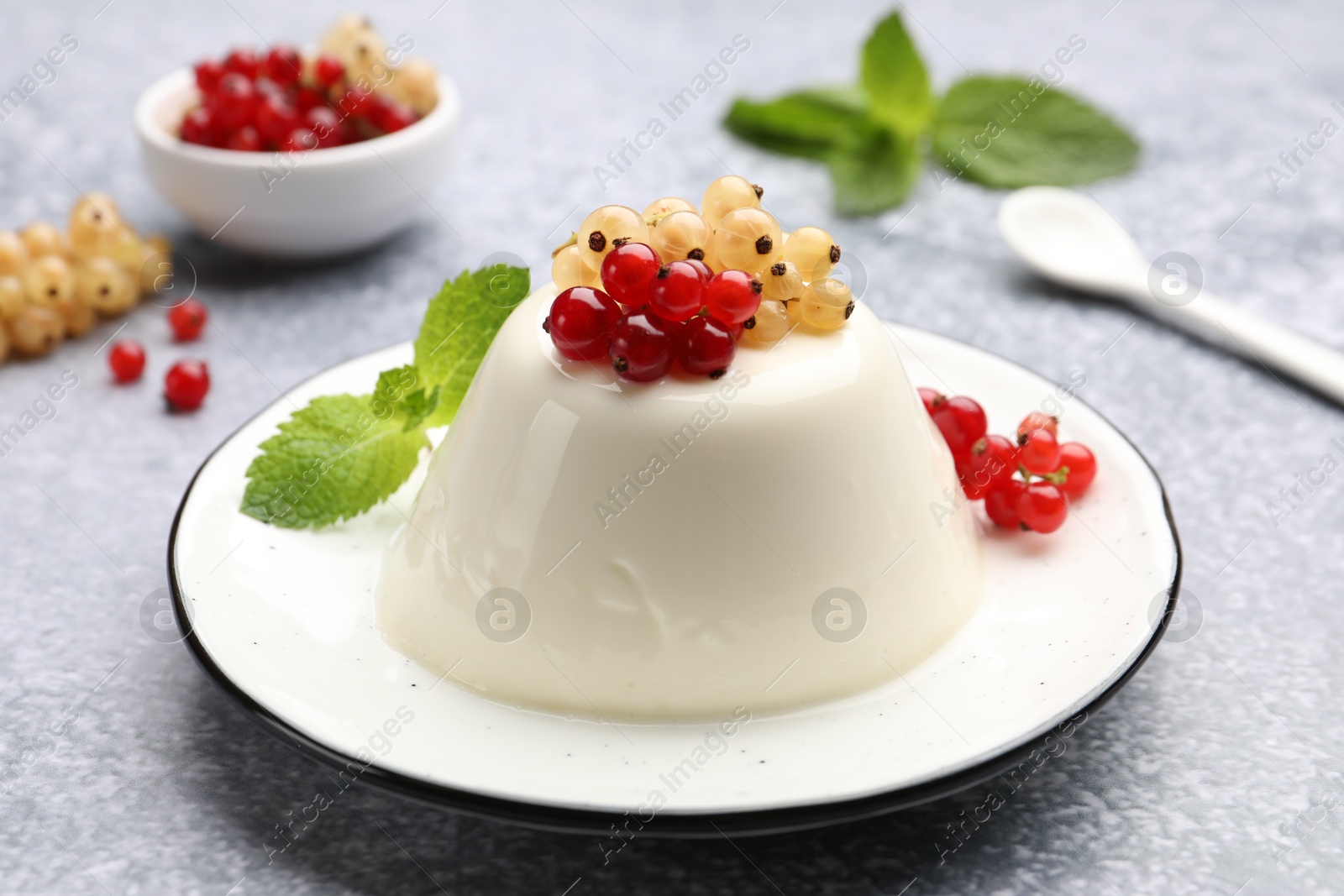 Photo of Tasty panna cotta with currants and mint on light grey table, closeup