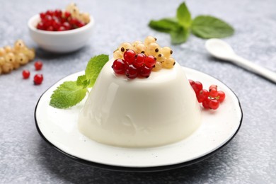 Photo of Tasty panna cotta with currants and mint on light grey table, closeup