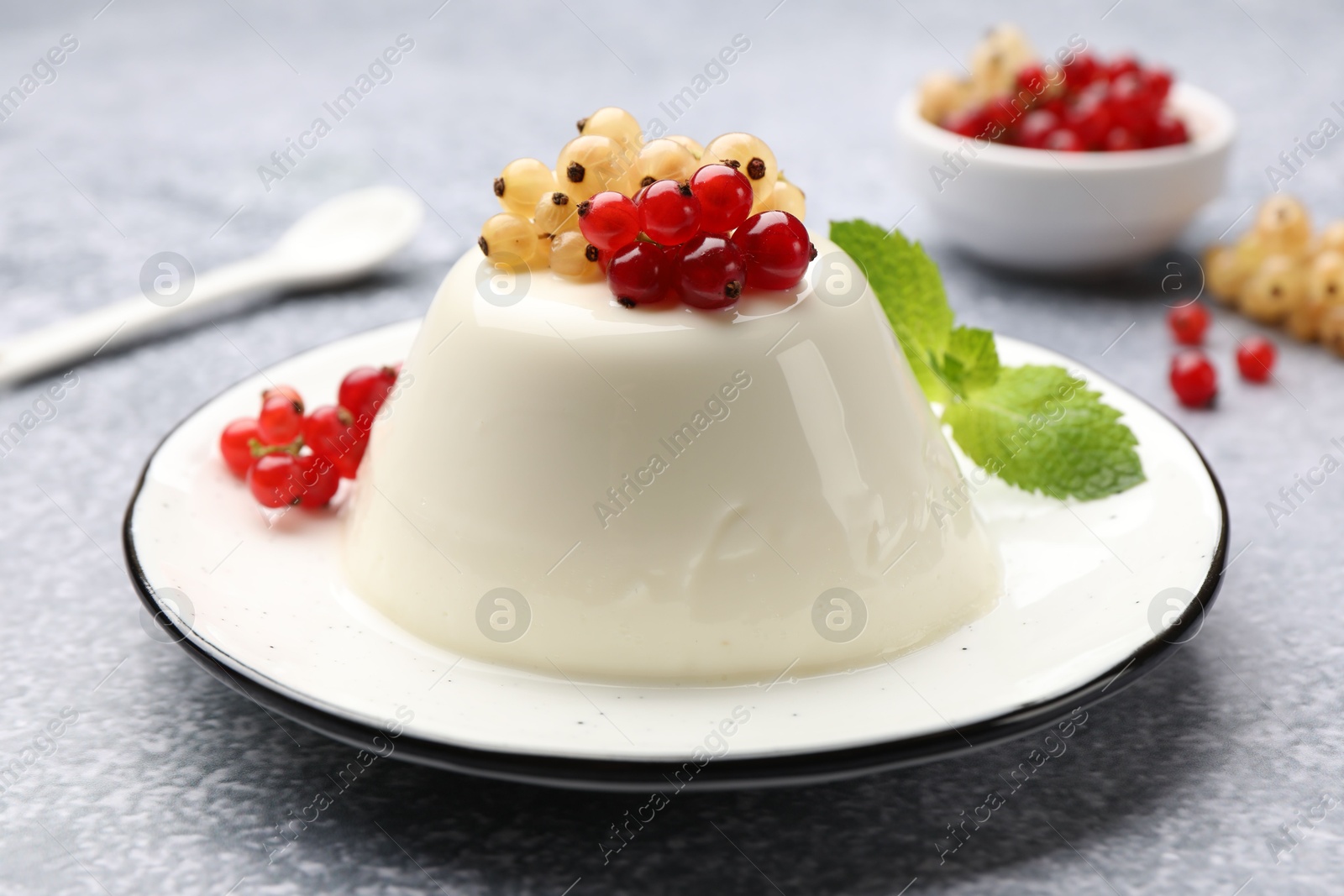 Photo of Tasty panna cotta with currants and mint on light grey table, closeup