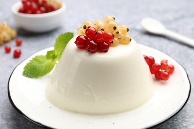 Photo of Tasty panna cotta with currants and mint on light grey table, closeup