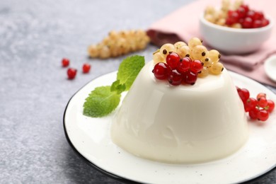 Photo of Tasty panna cotta with currants and mint on light grey table, closeup