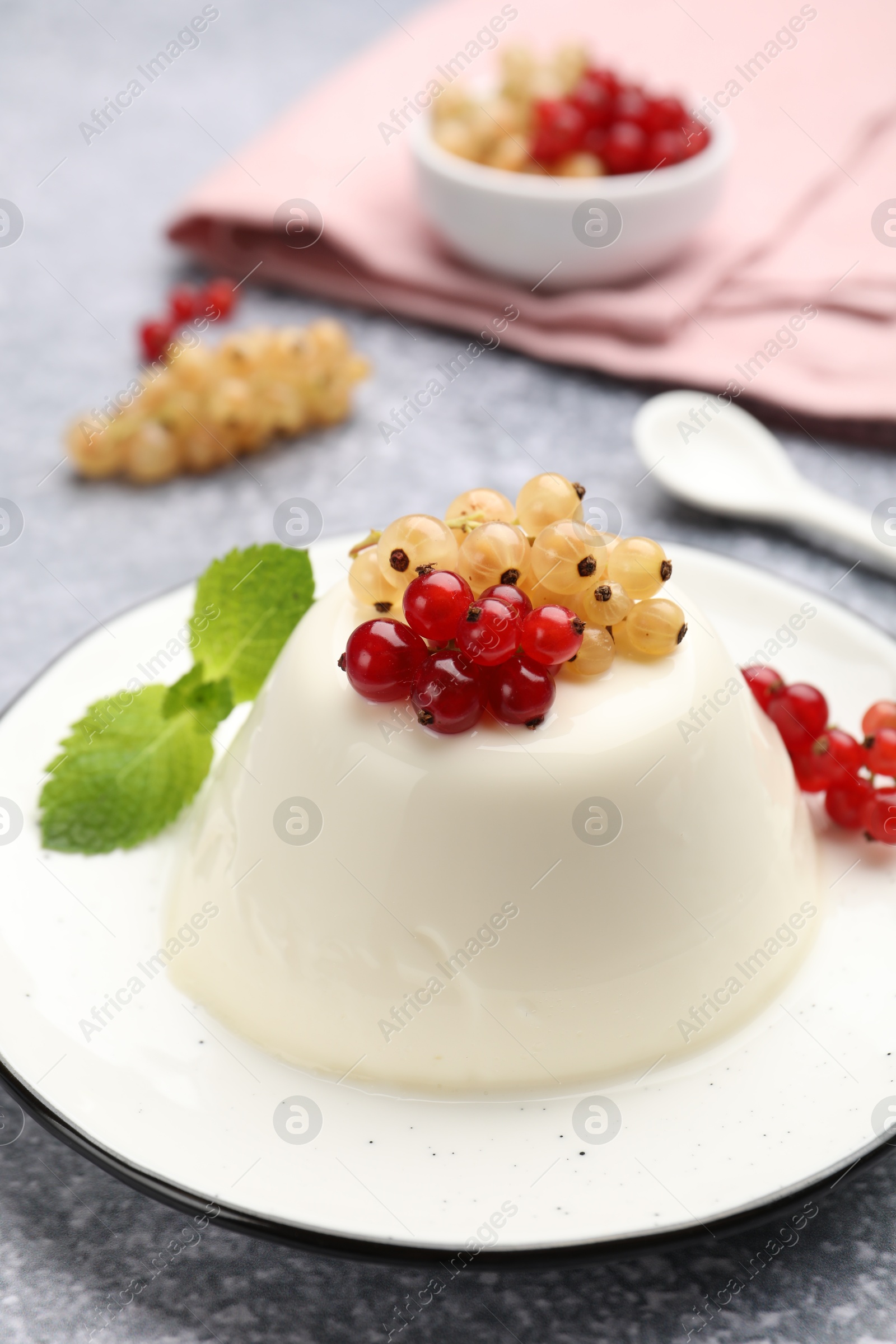 Photo of Tasty panna cotta with currants and mint on light grey table, closeup