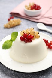 Photo of Tasty panna cotta with currants and mint on light grey table, closeup