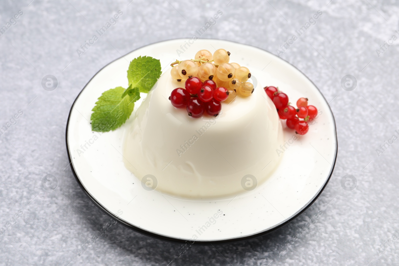 Photo of Tasty panna cotta with currants and mint on light grey table, closeup