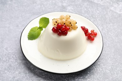 Photo of Tasty panna cotta with currants and mint on light grey table, closeup