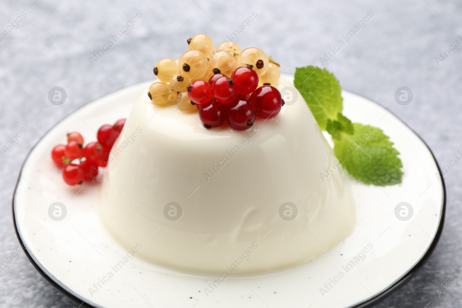 Photo of Tasty panna cotta with currants and mint on light grey table, closeup