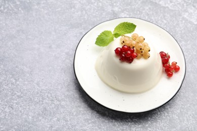 Photo of Tasty panna cotta with currants and mint on light grey table, closeup. Space for text