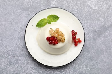 Photo of Tasty panna cotta with currants and mint on light grey table, top view