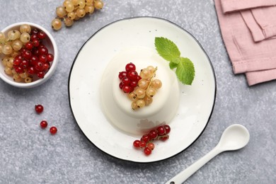 Photo of Tasty panna cotta with currants and mint on light grey table, flat lay